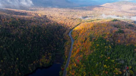 Aerial-view-of-a-lake-surrounded-with-peak-fall-colors-in-Upstate-New-York
