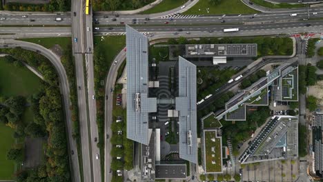 Like-mice-in-hurry,-vehicles-passing-highest-business-buildings,-Munich-city