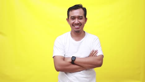 Portrait-of-a-asian-man-with-pleasant-smile-and-crossed-arms-isolated-on-yellow-wall