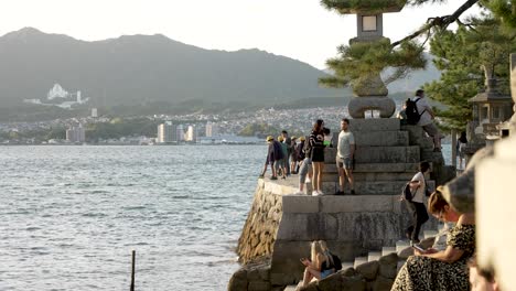 Turistas-En-El-Rompeolas-Junto-A-La-Bahía-De-Hiroshima-En-El-Santuario-Itsukushima-Durante-La-Puesta-De-Sol-De-La-Hora-Dorada