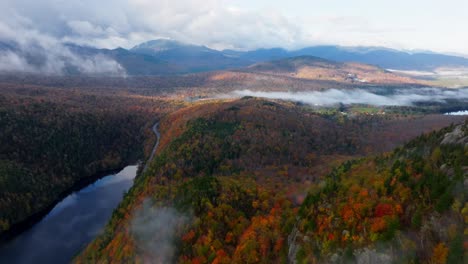Aerial-view-of-clouds-rolling-in-next-to-a-lake-in-Upstate-New-York-surrounded-with-fall-foliage