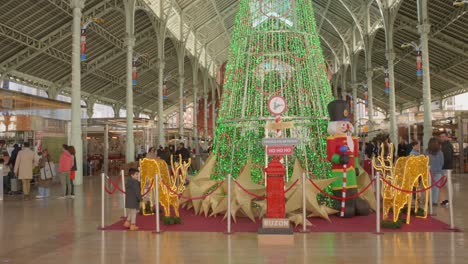 Pan-shot-of-large-Christmas-tree-during-December-festivities-at-Market-de-Colon-in-Valencia,-Spain
