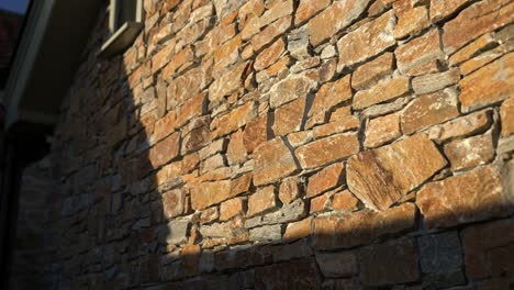 Parallax-movement-as-sunset-golden-hour-light-hitting-the-side-of-a-rustic-stone-walled-building-casting-harsh-shadows-with-luxury-feel