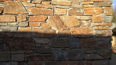 Sunset-golden-hour-light-hitting-the-side-of-a-rustic-stone-walled-building-casting-harsh-shadows-with-luxury-feel