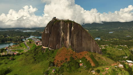 Drone-shot-circling-the-El-Peñón-monolith,-sunny-day-in-Guatape,-Colombia