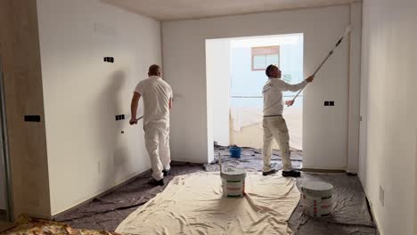 Two-craftsman-are-doing-painting-of-indoor-space,-using-white-color-painting-roller,-tradesman-responsible-for-the-painting-and-decorating-of-buildings