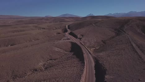 Drone-flight-over-winding-road-in-the-Atacama-Desert-with-arid-landscape-in-Northern-Chile,-South-America
