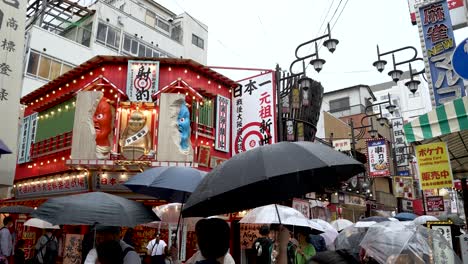 People-With-Umbrellas-Walking-Through-Shinsekai-Area-On-Rainy-Day