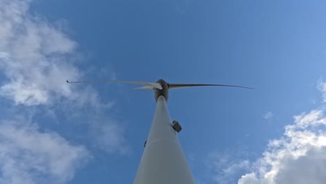 Looking-up-and-observing-wind-turbine-in-operation-on-sunny-day