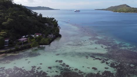 Bora-Bora-coast-road-aerial-reveals-cruise-ship-at-anchor-in-lagoon