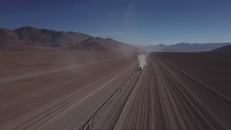 Epic-drone-shot-of-a-car-driving-on-deserted-dirt-road,-Bolivia-and-Chile-route