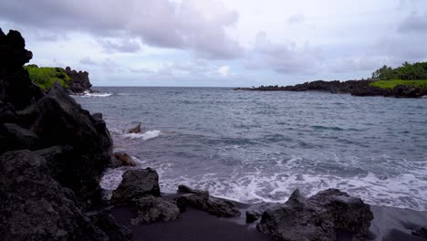 Hawaiian-Black-Sand-Beach-in-Waianapanapa-State-Park-along-the-Road-to-Hana-in-East-Maui,-Hawaii,-a-popular-tourist-destination-along-the-Road-to-Hana