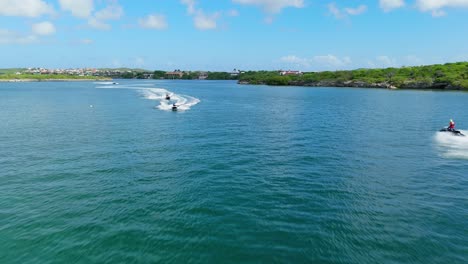 Aerial-push-in-as-jet-skis-approach-from-front-and-behind-driving-up-open-channel-in-Caribbean
