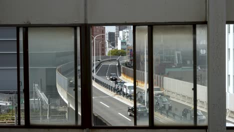Schuss-Durch-Fensterrahmen-Am-Bahnhof-Shin-Osaka-An-Einer-Überführungsstraße-Mit-öffentlichem-Verkehr