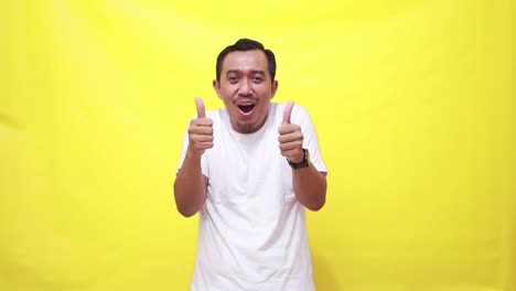 Happy-man,-dancing-and-thumbs-up-in-success,-good-job-or-winning-against-a-yellow-studio-background