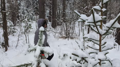 A-person-hiking-in-a-snowy-forest-with-a-saw-in-hand