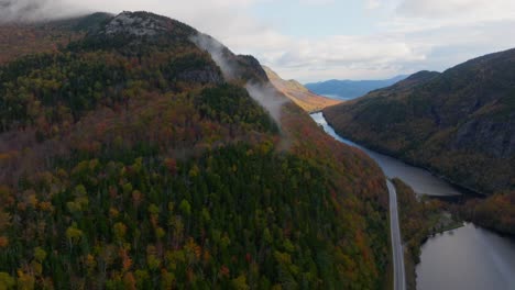 A-road-surrounded-with-a-lake-and-fall-foliage-in-Upstate-New-York-from-a-drone's-perspective