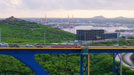 Pink-tourist-train-or-trolley-crosses-on-Juliana-bridge,-Willemstad-Curacao