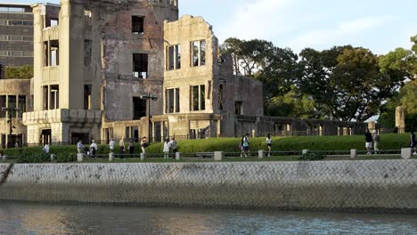 Fußgänger,-Die-Am-Wasser-Vor-Der-Atombombenkuppel-In-Hiroshima-Entlanggehen