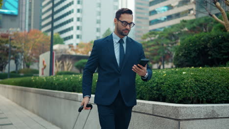 Businessman-walking-down-large-city-street-checking-phone
