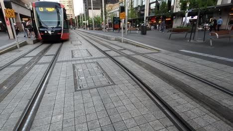 Handheld-Clip-Walking-Across-Light-Rail-Tracks-In-Front-Of-Tram,-Circular-Quay-Sydney