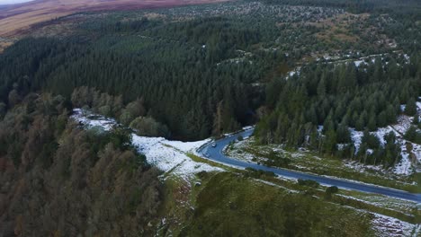 Aerial-View-of-a-Car-Driving-Through-Snow-Covered-Forest-In-The-Wicklow-Mountains,-With-People-Enjoying-The-Snowy-Forest-Backdrop