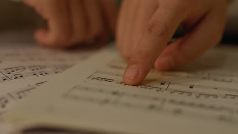 Close-up-on-girls-fingers-following-over-notation-in-the-music-score-book