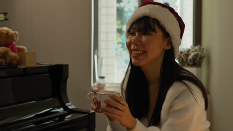 Two-pretty-Asian-twin-sisters-sit-by-the-piano-and-have-a-talk-in-warm-cosy-environment-at-home-on-Christmas-Day