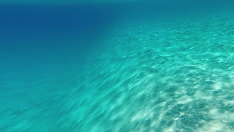 Underwater-view:-Steep-sandy-slope,-sun-reflects-off-turquoise-bottom
