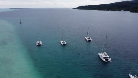 Lagoon-aerial-descends-to-catamaran-sailboats-moored-in-Polynesia