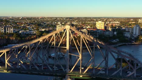 Cinematic-aerial-drone-fly-around-Brisbane-landmark-Story-bridge-capturing-busy-vehicle-traffics-crossing-the-river-between-Kangaroo-point-and-Fortitude-valley-and-people-on-sunset-adventure-climb