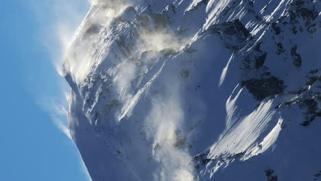 Powdery-snow-blows-off-mountain-peak,-Avoriaz-Ski-Resort,-French-Alps,-vertical
