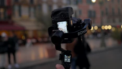 Close-up-of-sophisticated-DJI-Ronin-RS3-stabilizer-gimbal-with-professional-camera-mounted-filming-city-life-in-evening