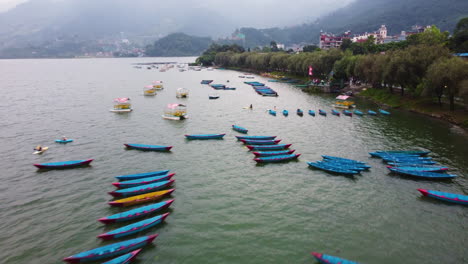 Drone-Sobre-El-Lago-Phewa-En-Nepal-Con-Barcos-Anclados-Y-Cordillera-En-El-Fondo---Paso-Elevado---Nepal,-Asia