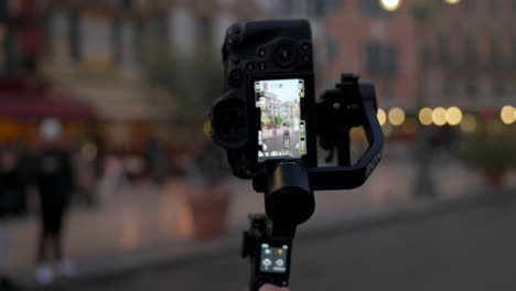 Close-up-of-sophisticated-DJI-Ronin-RS3-stabilizer-gimbal-with-professional-camera-mounted-filming-city-life-in-evening