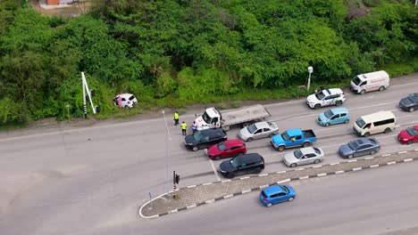 Cars-line-up-at-stop-light-as-yellow-vested-official-workers-asses-car-crash-situation