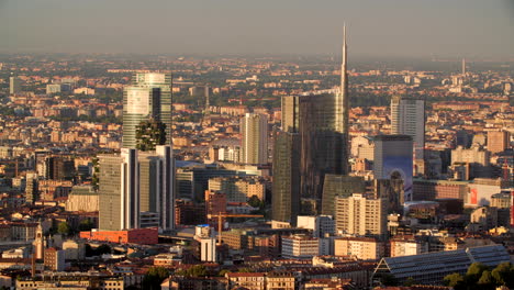 Milan-city-skyline-glow-during-sunset,-aerial-view