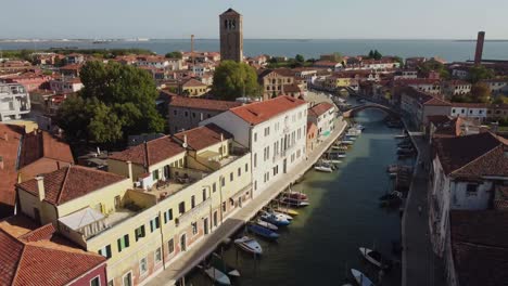 Boats-moored-near-building-in-canal-of-Venice,-aerial-ascend-view