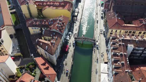 Iconic-pedestrian-bridge-over-water-canal-in-Milan,-aerial-orbit-view