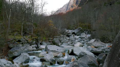 Pedestal-drone-shot-of-River-Maggia's-glacial-waters-flowing-down-from-Cristallina-Mountain,-to-the-village-of-Cavergno,-in-Vallemaggia-district,-in-the-canton-of-Ticino,-in-Switzerland