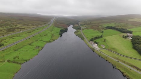Booth-wood-reservoir-aerial-view-following-the-freshwater-lake-alongside-the-M62-motorway-in-West-Yorkshire