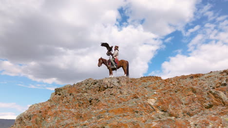 Eagle-Hunter-At-The-Top-Of-Cliff-In-Western-Mongolia---Drone-Shot