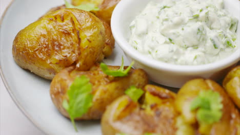 Rotating-white-plate-with-roasted-potatoes-and-dip