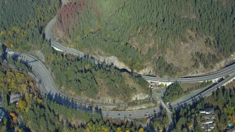 Aerial-View-of-Highway-with-Traffic-in-Mountainous-Sunny-Forested-Area