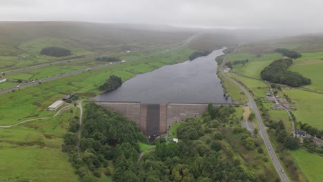 Booth-wood-reservoir-aerial-view-circling-above-the-concrete-lake-dam-and-M62-motorway
