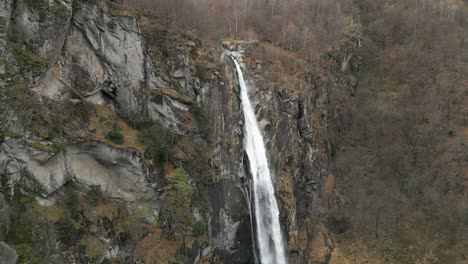 Snow-falling-in-front-of-a-cascading-Cascata-di-Foroglio-Waterfall,-located-in-Cavergno-village-in-the-district-of-Vallemaggia-in-the-canton-of-Ticino,-in-Switzerland