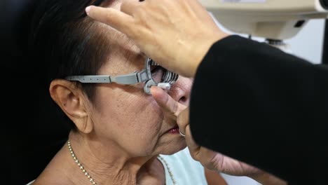 Using-a-trial-frame,-elderly-is-having-her-eyes-checked-manually-in-an-optical-shop-in-Bangkok,-Thailand