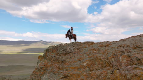 Eagle-Hunter-With-Trained-Eagle-On-A-Horse-Standing-On-The-Clifftop-In-Western-Mongolia