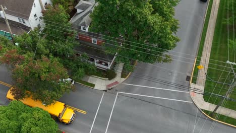 Yellow-school-bus-driving-on-American-town-street