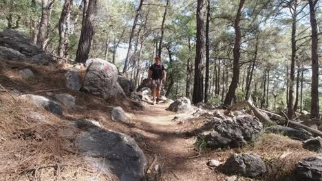Man-with-backpack-hiking-in-middle-of-rocky-mountainous-forest-in-Lycian-Way,-Turkey